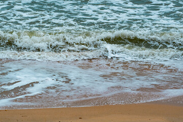 Fototapeta premium Beautiful sea wave splashing on golden sand beach at Pattaya City, the resort city of Thailand.