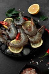 Large King prawns on lemon slices and ice. Hot peppers. Black plate. Black background