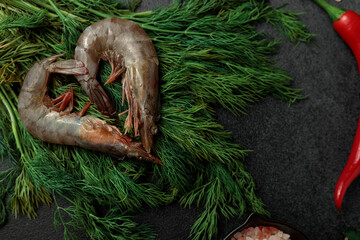 Large King prawns on lemon slices and ice. Hot peppers. Black plate. Black background