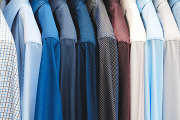 A row of shirts hanging on a clothesline, with the blue shirt on the left and the white shirt on...