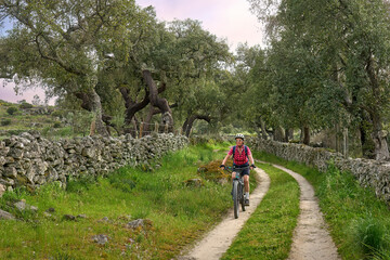 Fototapeta premium active senior woman cycling with her electric mountain bike in the rough landscape of National Parc Serra de São Mamede near Marvao in central Portugal, Europe