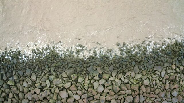 Sea waves hitting rocks on a sea dyke, overhead drone stationary shot