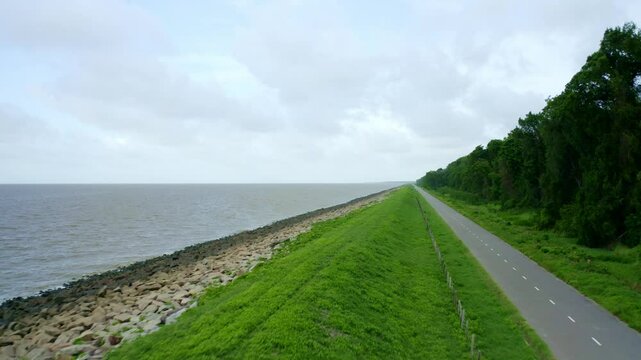 Aerial: Sea dyke view along the asphalt road flyover, North Atlantic Ocean and Nickerie Suriname
