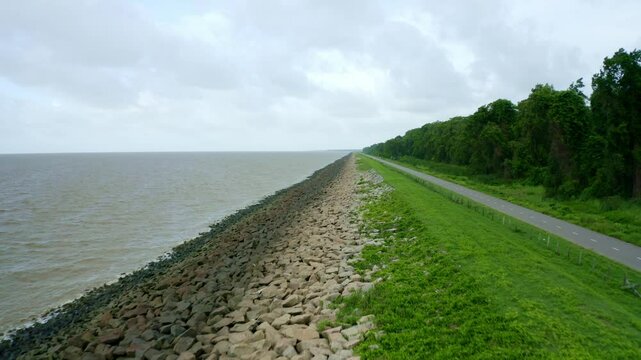Aerial: Sea dyke view along the asphalt road, drone flying fast backwards, North Atlantic Ocean and Nickerie Suriname