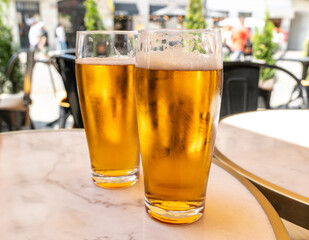 Beer glass in sunny day, cold pint glass with remaining beer on outdoor table, cool condensation