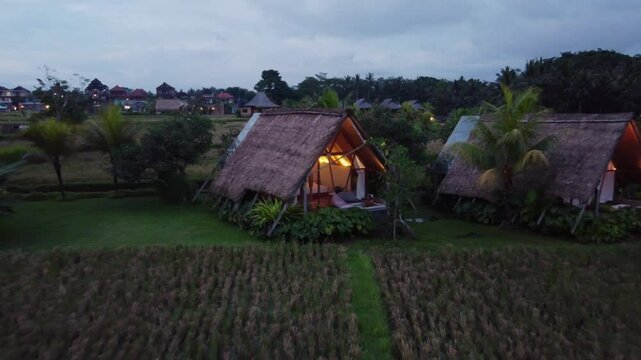 Person Relaxing in Outdoor Bathtub of Cabin Hut in Rural Balinese Nature in the Evening, Drone Shot