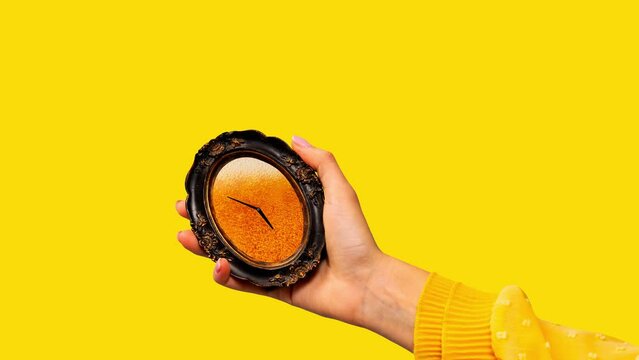 Stop motion, animation. Hand holding vintage clock with beer texture inside against bright yellow background. Contemporary art. Concept of summer vibe, surrealism, abstract creative design, pop art