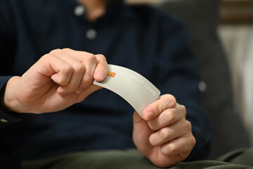 Close up upset young man breaking his credit card. Financial problems and debt free concept