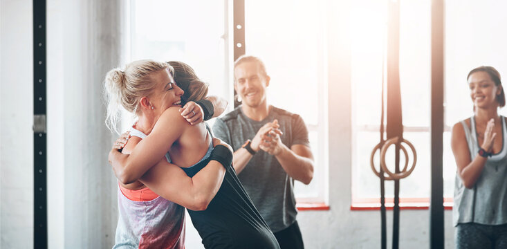 Fitness, women and celebration hug at gym for support after workout, sports exercise or training challenge. Happy girls, embrace and friends, people smile and achievement together for wellness club
