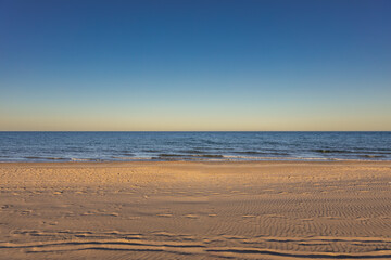 Beautiful sunset landscape of sandy sea and blue sky.