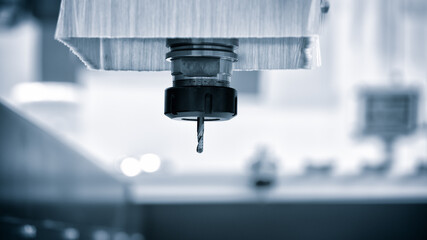 A cnc machine with a drill bit in it. The machine is black and silver