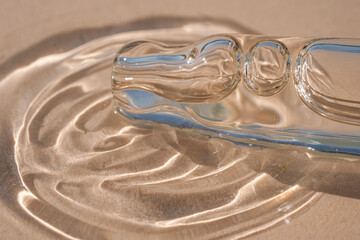 A dropper and a drop of cosmetic oil on a beige background.