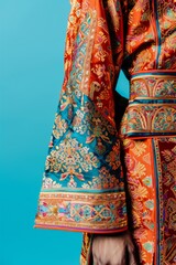 Naklejka premium A vibrant, traditional garment with intricate patterns, showcasing rich cultural heritage against a turquoise background. Close-up shot.