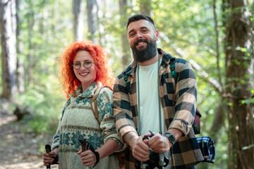 Fototapeta premium A beautiful and cheerful couple is hiking in the forest enjoying nature and each other's company