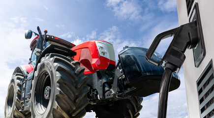 Electric vehicles charging station on a background of agricultural tractor. Concept.