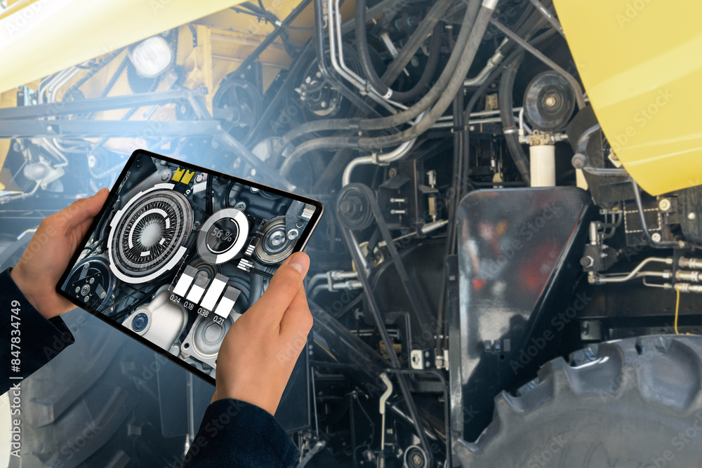 Poster serviceman with digital tablet next to combine harvester with open hood