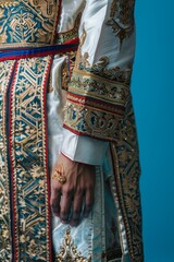Close-up of a person's hand in traditional, ornate clothing with intricate embroidery, showcasing cultural heritage and rich craftsmanship.