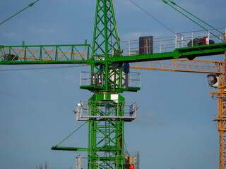 Yellow and green construction tower cranes against blue sky. Construction site. Architectural concept. Industry. Ust-Kamenogorsk (kazakhstan)