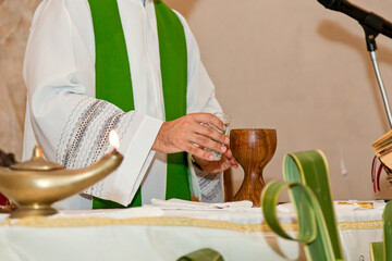 Priest in a green chasuble getting the chalice ready for holy mass in the church