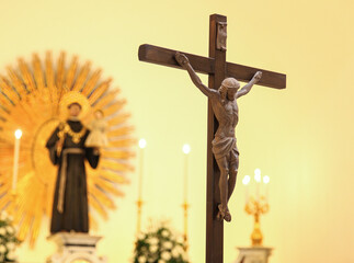 Blurred religious statue in background of church with wooden crucifix, symbolizing faith,...