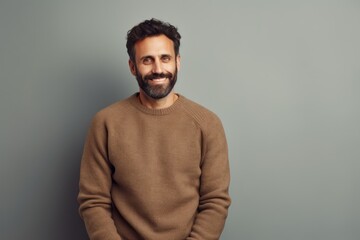Obraz premium Portrait of a satisfied man in his 30s wearing a cozy sweater on minimalist or empty room background