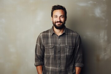 Fototapeta premium Portrait of a glad man in his 30s wearing a comfy flannel shirt in minimalist or empty room background