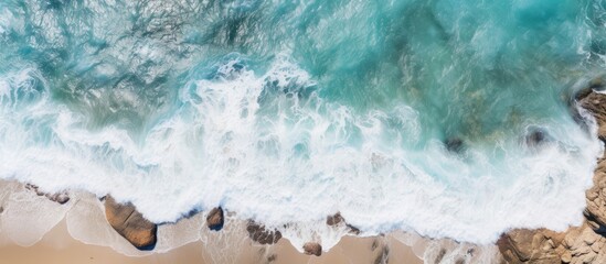 Obraz premium Top view of sea waves hitting rocks Aerial view of sea water and beach coast with stones. Creative banner. Copyspace image