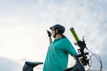 Obraz premium A young person, wearing a helmet and a shirt, looks up at the sky while riding a bicycle. The cyclists hand is on the handlebars, and the bikes seat is visible in the foreground.