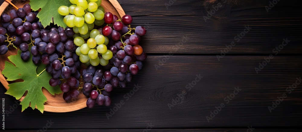 Poster top view of various types of grapes on vintage plate on black wooden surface. creative banner. copys