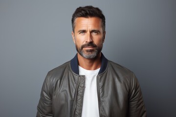 Portrait of a glad man in his 40s wearing a trendy bomber jacket isolated in minimalist or empty room background