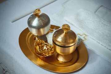 Golden chrism oil standing on a golden tray with a golden shell for a baptism ceremony