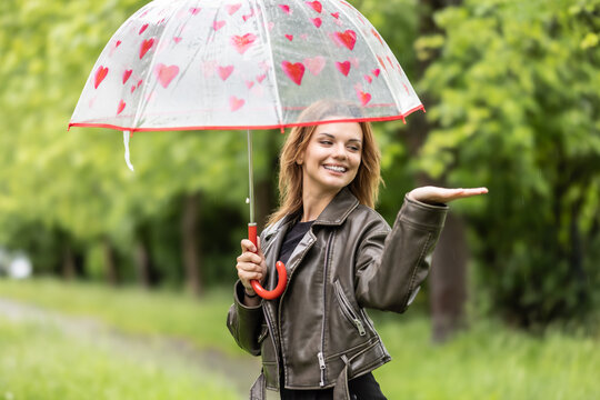 A cute young lady under an umbrella is trying to see if it is still raining