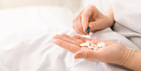 Senior woman holding pills in hand, taking medication from palm, close-up