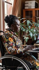 A woman sits in a wheelchair, focused on typing on a laptop computer