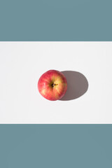 Una manzana roja sobre un soporte blanco y fondo verde. Vista superior	