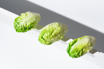 Tres corazones de lechuga fresca para ensalada sobre un soporte blanco. Vista superior