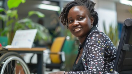 A woman with dreadlocks sits in an office, smiling at the camera