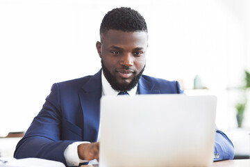 Hard-working african american man typing on laptop in office, empty space
