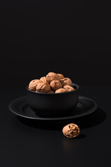 Nueces doradas en un recipiente negro sobre fondo negro