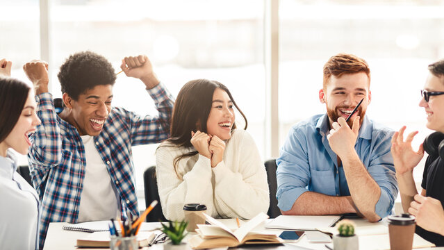 A diverse group of students are seated around a conference table, engaged in laughter and animated conversation. They appear to be enjoying a moment of camaraderie and shared humor