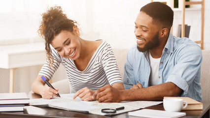 Obraz premium African-american couple planning honeymoon vacation with map, preparing for trip