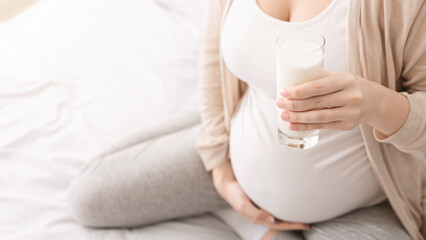 Concept of healthy nutrition and pregnancy. Belly of pregnant woman and glass of fresh milk, free...