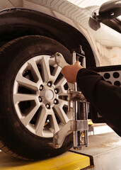 Auto mechanic installing sensor during suspension adjustment and automobile wheel alignment work at repair service station. Close up
