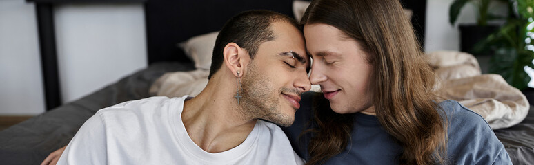 Fototapeta premium A young gay couple shares a tender moment in their bedroom, their foreheads touching as they close their eyes.