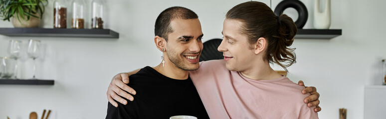 A young gay couple shares a tender moment in their modern kitchen, their smiles reflecting their love and happiness.