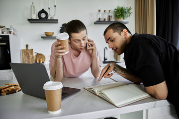 A young gay couple enjoys a morning coffee and plans their day in their modern kitchen.