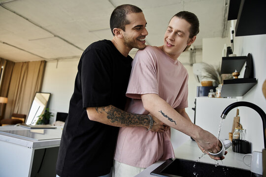 A young gay couple embraces in a modern kitchen, showcasing love and affection during daily routines. - Powered by Adobe
