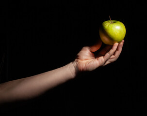 green apple in hand on black background