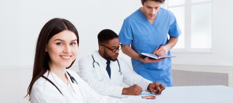 Team of doctors having meeting in medical office, woman looking at camera
