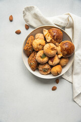 Variety of homemade Italian sweets typical for Sardinia region. Pardulas, amaretti, papassine and pizzicchi in bowl on white table.